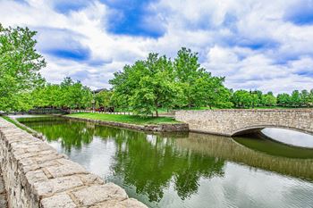 A stone wall borders a body of water with a bridge crossing over it